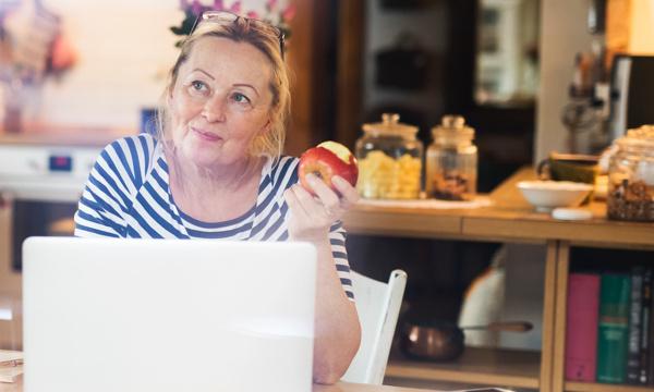 Woman eating apple at her laptop