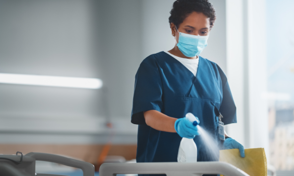 A nurse/cleaner disinfecting a hospital room.